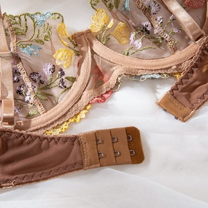 Detailed close-up of floral embroidery on sheer mesh bra with adjustable straps