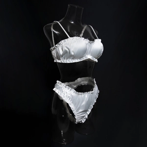 Detail of white satin lingerie set with ruffled edges and ruched texture on mannequin
