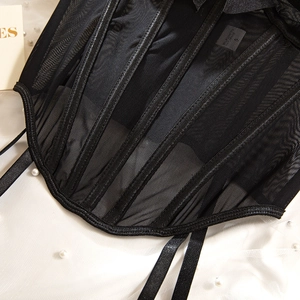 Detailed view of black mesh corset featuring structural boning and satin ribbon straps