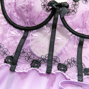 Détails de broderie sur lingerie en dentelle lilas avec nœud en satin noir chic