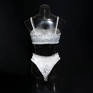 Detail of white satin lingerie set featuring pleated ruffles and silky texture on a mannequin
