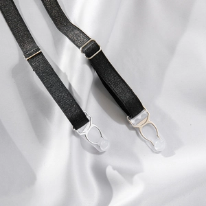 Detail of black adjustable elastic garter straps with silver metal clips on white fabric