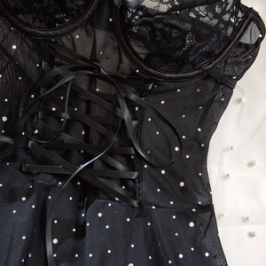 Detail of black lace bodice with iridescent sequins and adjustable ribbon corset ties