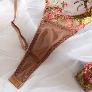 Detailed macro view of colorful floral embroidery and mesh texture on coffee lace bra