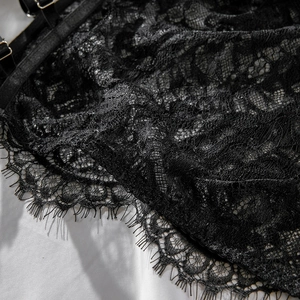 Close-up of black floral lace fabric with delicate eyelash trim and adjustable strap detail