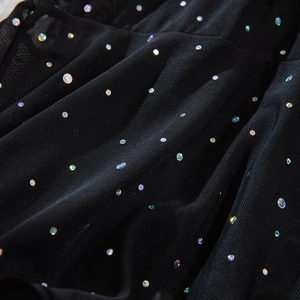 Close-up of black mesh fabric with sparkling iridescent rhinestones on a sexy dress