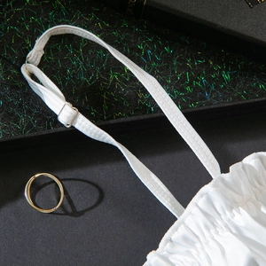 Detail of white lingerie strap with adjustable metal buckle and pleated fabric texture