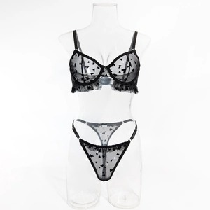 Détail d'un ensemble de lingerie en maille noire avec flocage cœurs et bords volantés