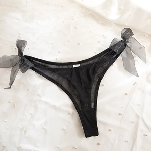 Detail of black mesh thong featuring large organza bows and delicate pearl background