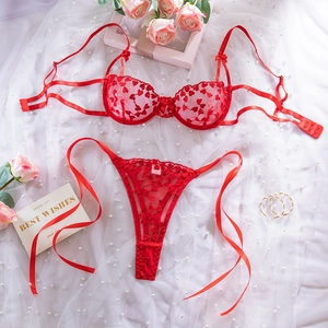 Vista dettagliata di un set lingerie in pizzo rosso con ricamo a cuore e fiocchi
