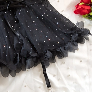 Detail of sexy black mesh lingerie with colorful rhinestones and floral petal ruffles