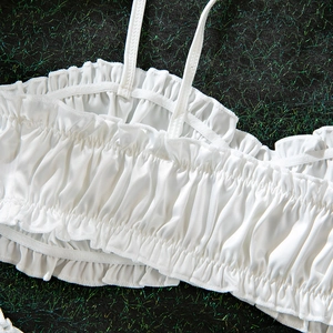 Detail of white pleated camisole top with ruffled edges and thin shoulder straps
