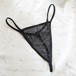 Close-up of black mesh G-string with colorful rhinestones on a white pearl background