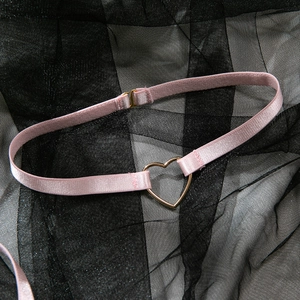 Détail de la sangle en satin rose clair avec boucle en métal doré en forme de cœur