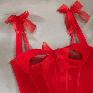 Detailed view of red mesh corset with satin bows, cut-out design, and Savage brand label
