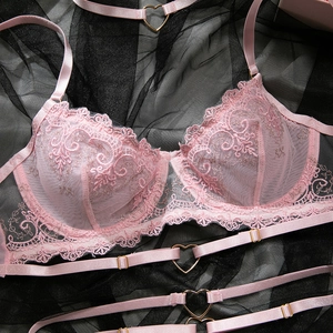 Détail d'un soutien-gorge en dentelle rose avec boucles en métal cœur et broderie fine
