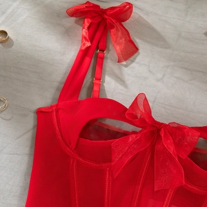 Detail of red mesh corset top featuring boning seams and large organza bows on straps