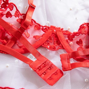 Dettaglio del ricamo in pizzo rosso con spalline regolabili e chiusura posteriore