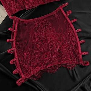 Detailed close-up of dark red lace garter belt with adjustable satin straps and metal clips