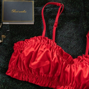 Detail of red satin lingerie top featuring ruffled textures and adjustable straps