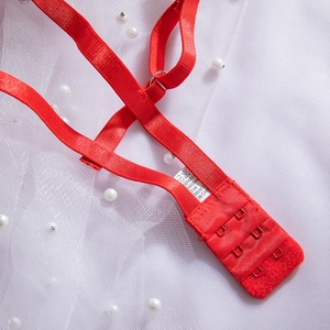 Dettaglio del retro di un reggiseno in pizzo rosso con spalline regolabili e ganci in metallo