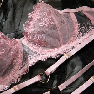 Détail de broderie en dentelle rose avec anneaux métalliques en forme de cœur