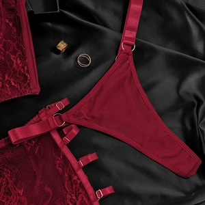 Detail of wine red lace lingerie set with satin straps and metallic rings on silk