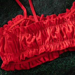 Macro shot of red satin lingerie set featuring pleated ruffle texture and thin straps