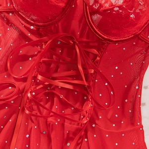 Detail of red lace lingerie featuring sequin accents and a satin ribbon lace-up design