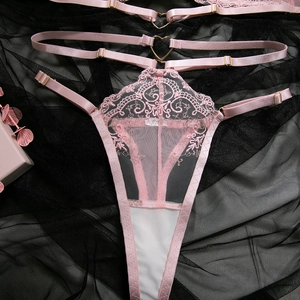 Détail d'un string en dentelle rose avec boucle en métal coeur et bretelles
