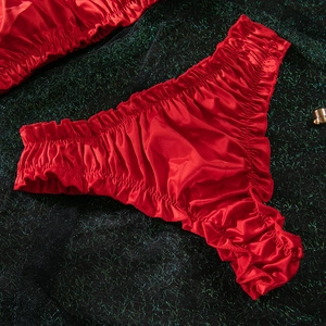Detail of red satin lingerie set with ruffled edges on a dark green glitter background