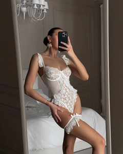 Detail of white lace bodysuit featuring floral embroidery and matching leg rings
