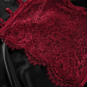 Close-up of dark red lace lingerie with floral patterns and velvet straps on silk background