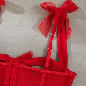 Detail of red mesh corset with organza bow straps and adjustable gold metal buckles