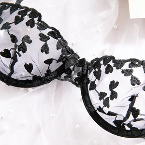 Dettaglio reggiseno in pizzo nero con ricamo a cuore e fiocco di seta decorativo