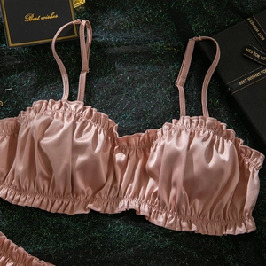 Detailed macro view of pink satin bra with elegant ruffle trim and adjustable silk straps