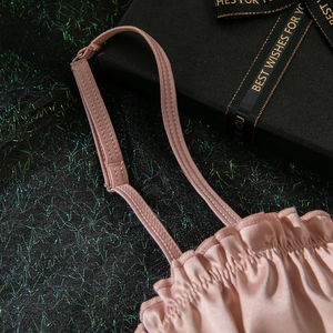 Detail of light pink satin lingerie with adjustable straps and ruffled neckline trim