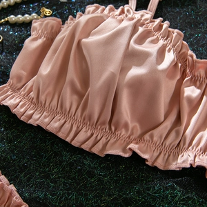 Close-up of rose pink satin camisole with ruffled edges and elegant pearl accents