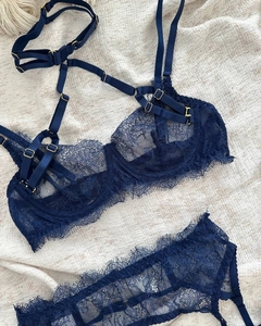 Detail of navy blue eyelash lace lingerie with gold metal buckles on textured fabric
