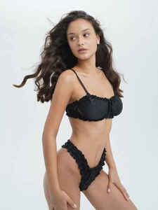 Detail of black pleated bikini set featuring ruffle trim and thin shoulder straps