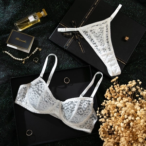Detailed flat lay of white leopard lace lingerie set in a luxury gift box with dry flowers
