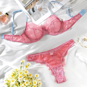 Flat lay of pink lace lingerie set with light blue straps and pearl accessories