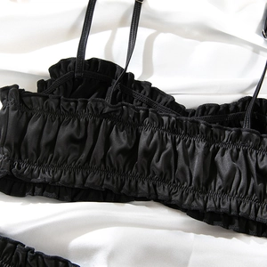 Detail of black satin lingerie featuring elastic smocked texture and ruffled edges