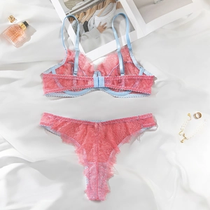 Detailed view of pink lace lingerie set with blue straps on soft white fabric