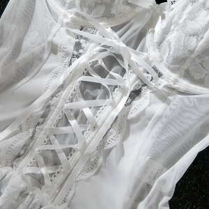 Close-up of white lace bodice featuring intricate mesh details and ribbon bow tie