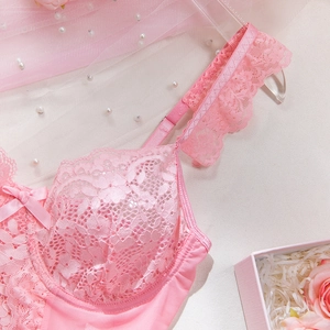 Detail of pink floral lace bra featuring ruffled straps and delicate bow accent