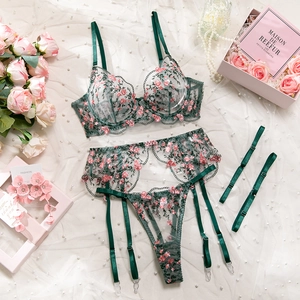 Detailed close-up of dark green mesh lingerie set with pink floral embroidery and metal garter clips