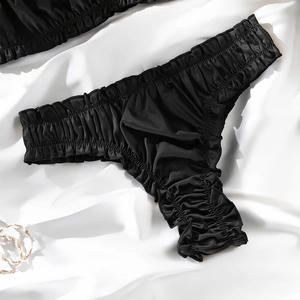 Detailed view of black satin panties with elegant ruffled edges and silky smooth texture