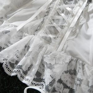 Detail of white lace corset top with satin ribbon ties and double-layered ruffles
