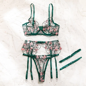 Detailed flat-lay of emerald green embroidery lingerie set with floral mesh and garter
